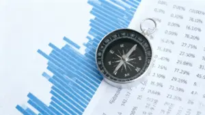 Una bussola su grafici e tabelle con dati finanziari stampati su carta