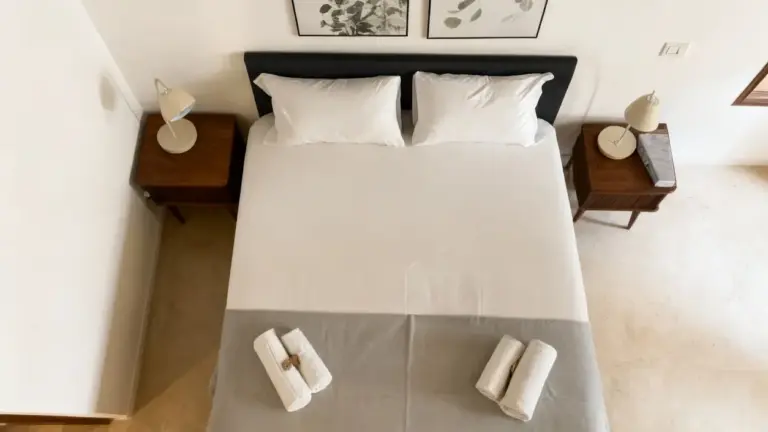 Letto matrimoniale pulito con due asciugamani arrotolati in una camera ben ordinata