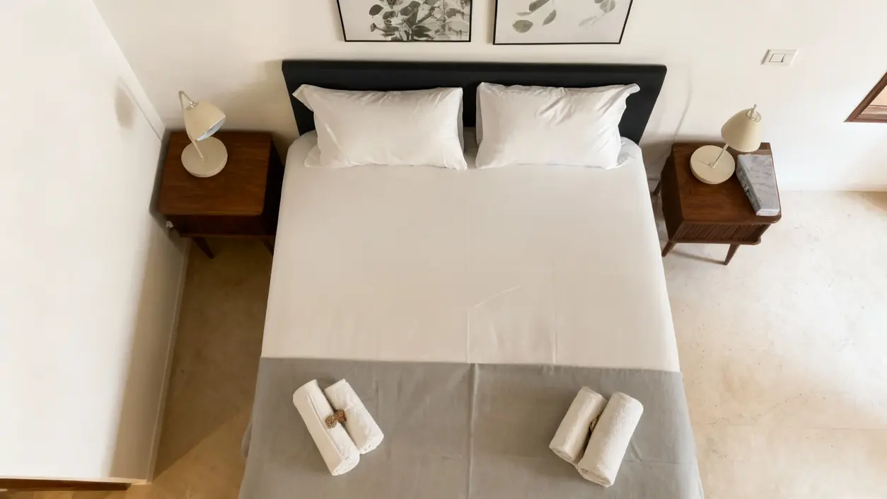 Letto matrimoniale pulito con due asciugamani arrotolati in una camera ben ordinata