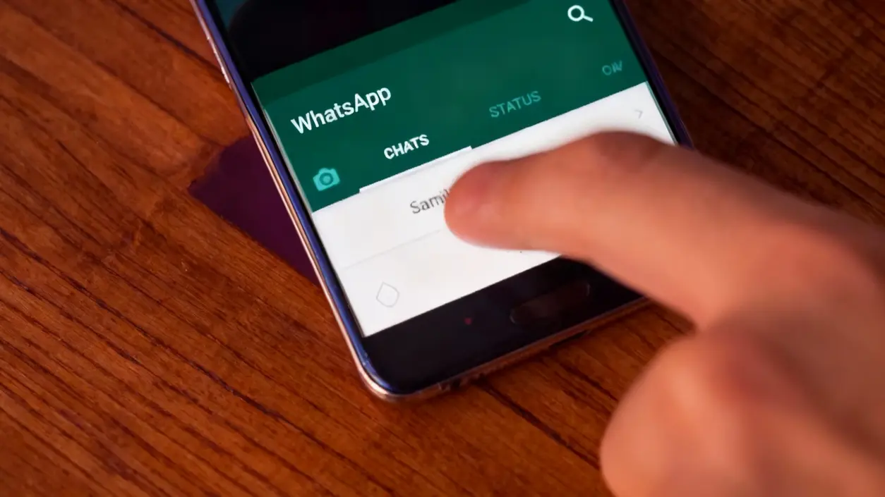 Una mano interagisce con l'app WhatsApp su uno smartphone