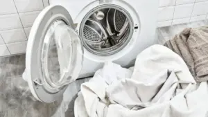 Asciugamani e biancheria davanti a una lavatrice aperta in una lavanderia domestica