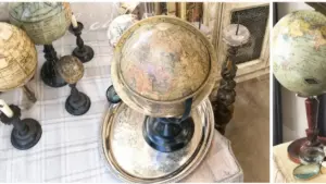 Vecchi mappamondi scolastici su tavolo antico con candelabri e accessori vintage.